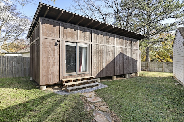 back of property with a lawn and an outdoor structure