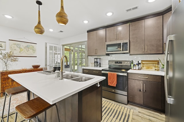 kitchen with a kitchen bar, sink, stainless steel appliances, and dark brown cabinets