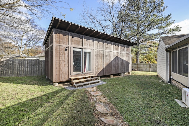 rear view of house featuring a lawn and an outbuilding