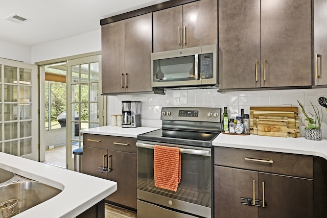 kitchen featuring decorative backsplash, light wood-type flooring, dark brown cabinetry, and appliances with stainless steel finishes