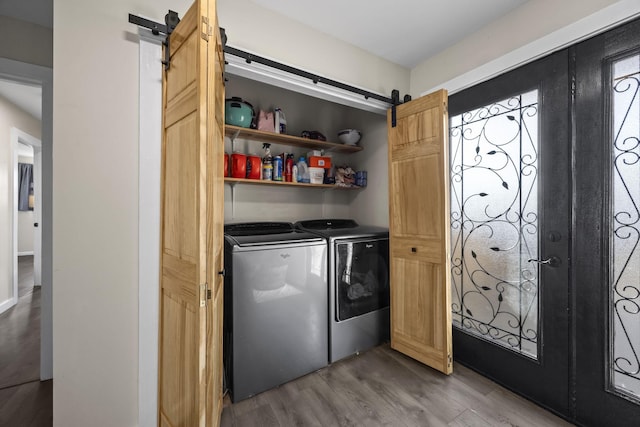 laundry area featuring washer and dryer, a barn door, and hardwood / wood-style flooring