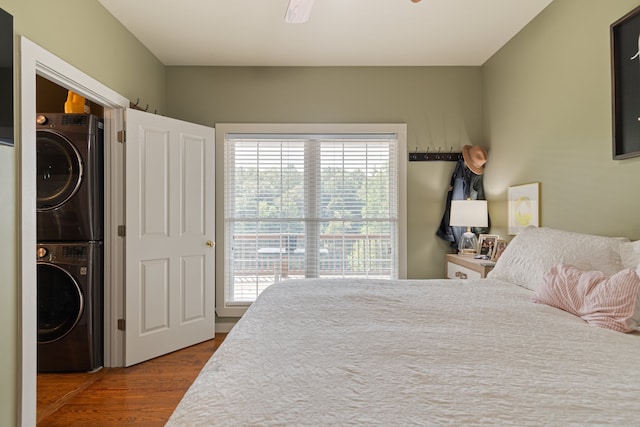 bedroom with multiple windows, hardwood / wood-style flooring, stacked washer / dryer, and ceiling fan