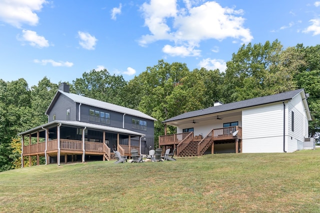 rear view of house featuring a fire pit, ceiling fan, and a yard