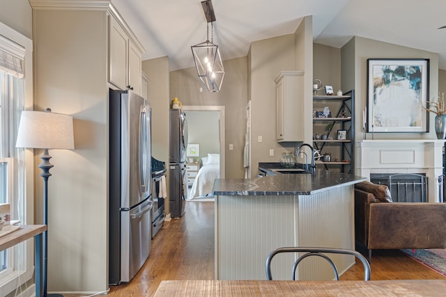 kitchen featuring stainless steel refrigerator, white cabinets, pendant lighting, and lofted ceiling