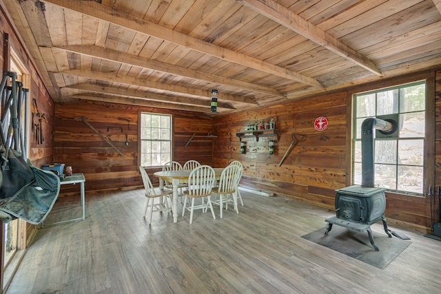 unfurnished dining area featuring wood ceiling, wooden walls, lofted ceiling with beams, hardwood / wood-style floors, and a wood stove