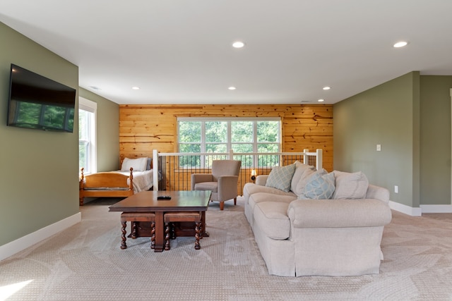 living room featuring wood walls, plenty of natural light, and light colored carpet