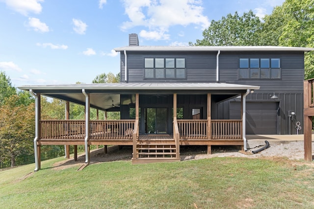 back of property featuring a garage, ceiling fan, a lawn, and a wooden deck