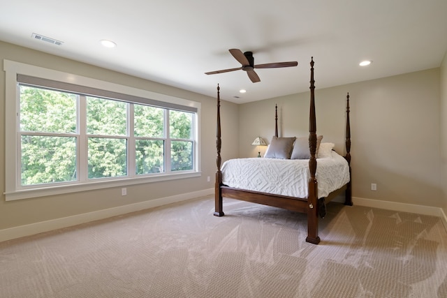 bedroom featuring ceiling fan, light colored carpet, and multiple windows