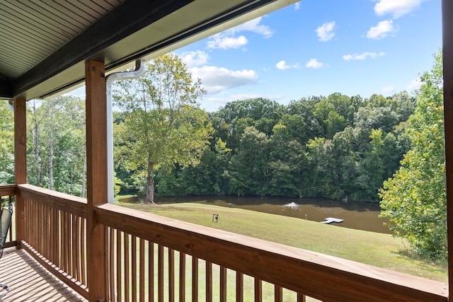 wooden terrace featuring a water view and a lawn