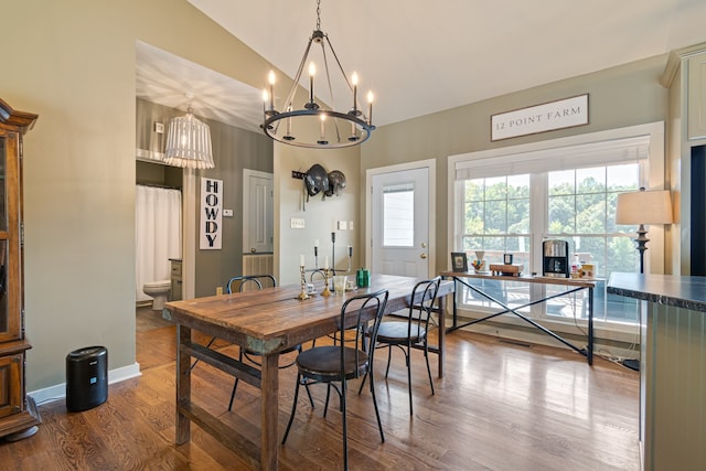 dining room featuring wood-type flooring, an inviting chandelier, and lofted ceiling