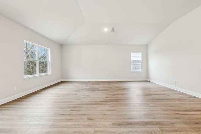 spare room featuring light wood-type flooring and lofted ceiling