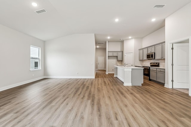 kitchen with a center island with sink, sink, gray cabinets, light hardwood / wood-style floors, and stainless steel appliances