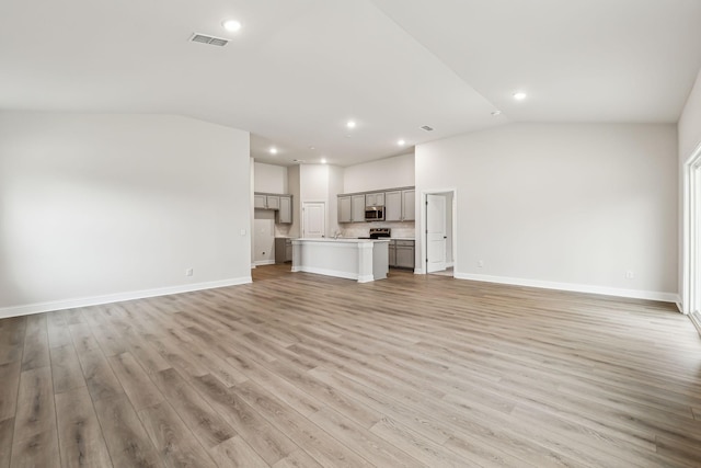 unfurnished living room featuring light hardwood / wood-style floors and vaulted ceiling