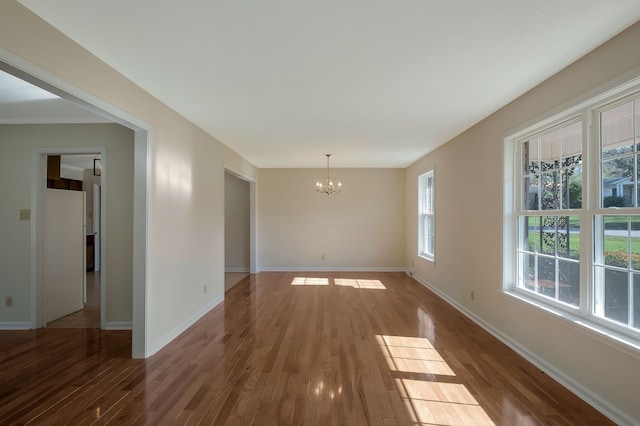 spare room featuring hardwood / wood-style flooring, plenty of natural light, crown molding, and an inviting chandelier