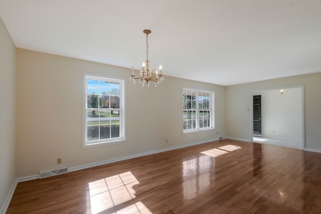 spare room featuring a chandelier and hardwood / wood-style flooring