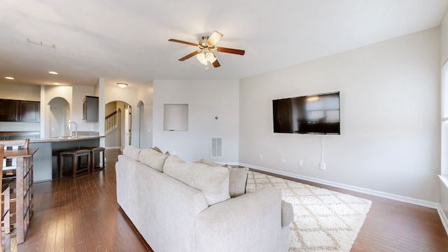 living room with dark hardwood / wood-style floors, ceiling fan, and sink