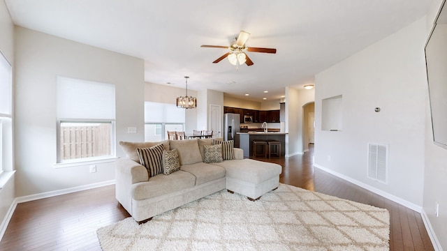 living room featuring hardwood / wood-style floors, ceiling fan with notable chandelier, and sink