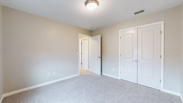 unfurnished bedroom featuring light colored carpet and a closet