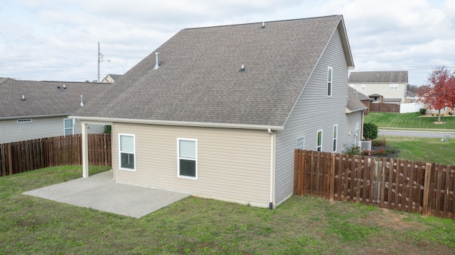 rear view of house with central AC unit, a patio area, and a lawn