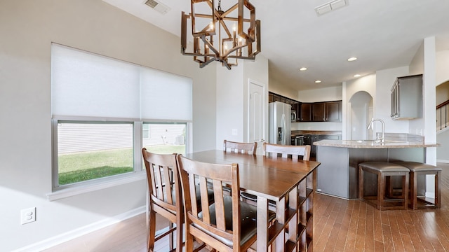 dining area with sink, dark hardwood / wood-style floors, and an inviting chandelier