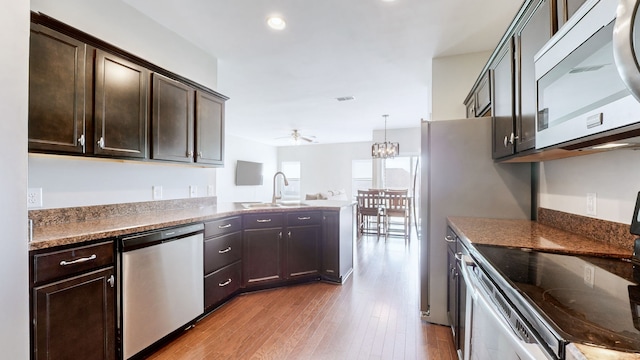 kitchen with dark brown cabinetry, light hardwood / wood-style flooring, ceiling fan with notable chandelier, and appliances with stainless steel finishes