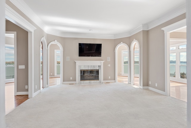 living room featuring a fireplace, a water view, light colored carpet, and ornamental molding