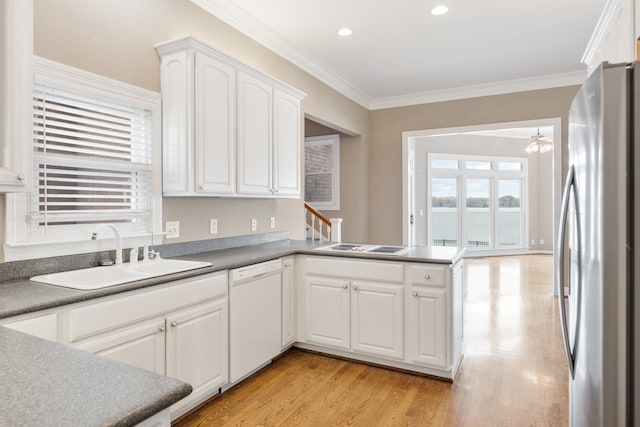 kitchen with dishwasher, sink, ornamental molding, white cabinetry, and stainless steel refrigerator