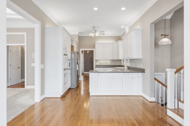 kitchen featuring white cabinetry, sink, ceiling fan, light hardwood / wood-style floors, and decorative light fixtures