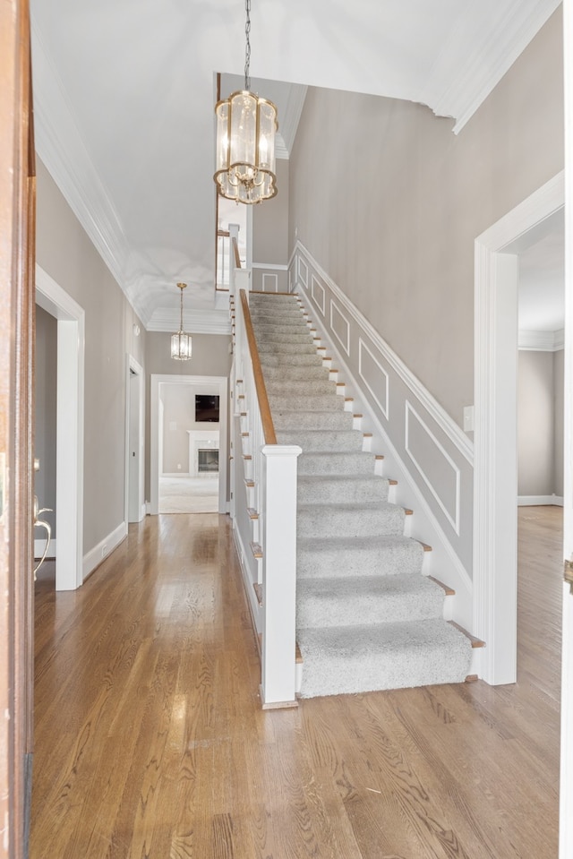 entryway with crown molding, hardwood / wood-style floors, and a notable chandelier