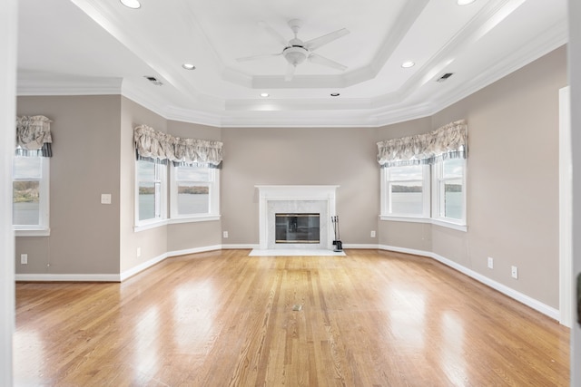 unfurnished living room featuring crown molding, plenty of natural light, a high end fireplace, and light hardwood / wood-style floors