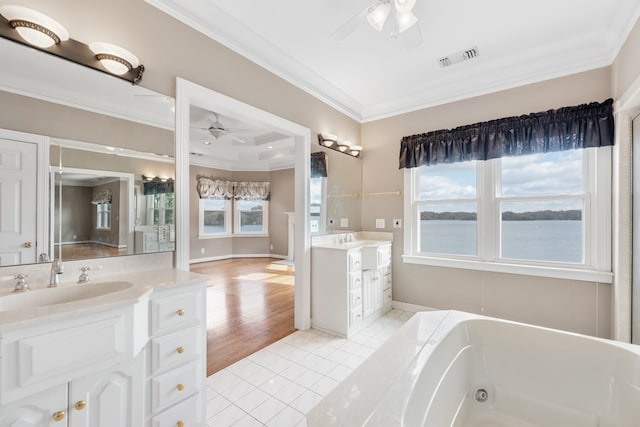 bathroom with tile patterned floors, vanity, ceiling fan, crown molding, and a water view