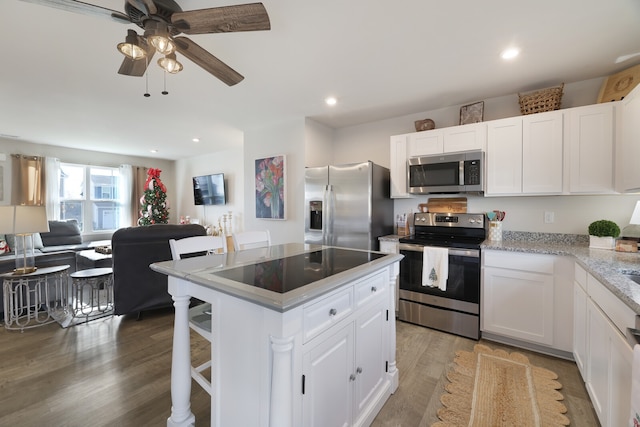 kitchen with ceiling fan, hardwood / wood-style floors, white cabinets, and stainless steel appliances