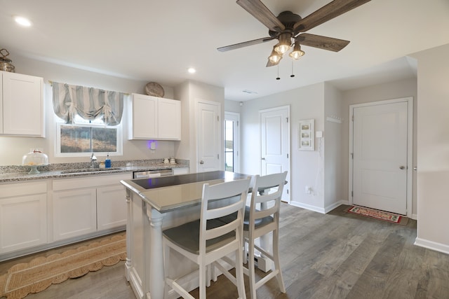 kitchen featuring light stone countertops, ceiling fan, dark wood-type flooring, sink, and white cabinets