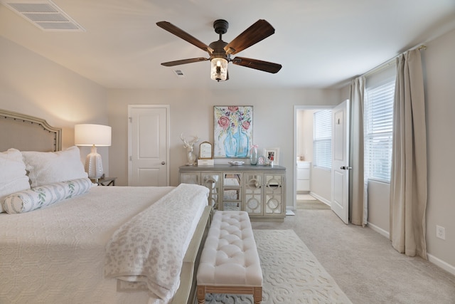 bedroom featuring light carpet, ensuite bathroom, and ceiling fan