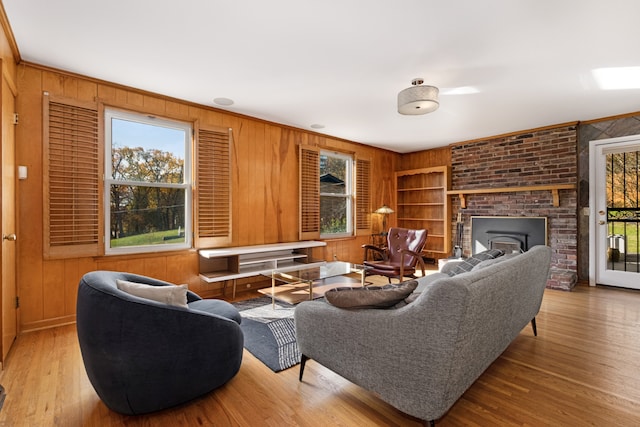 living room with a healthy amount of sunlight, wooden walls, and light hardwood / wood-style flooring