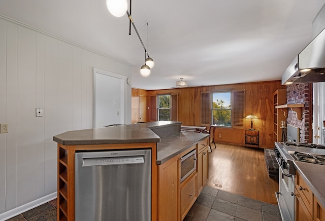 kitchen with dark hardwood / wood-style flooring, stainless steel appliances, wooden walls, a fireplace, and a kitchen island