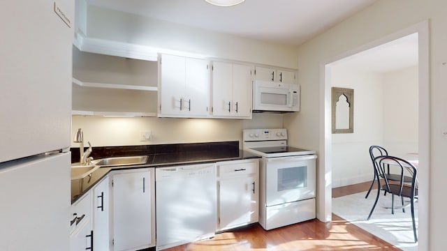 kitchen with sink, white appliances, light hardwood / wood-style floors, and white cabinets