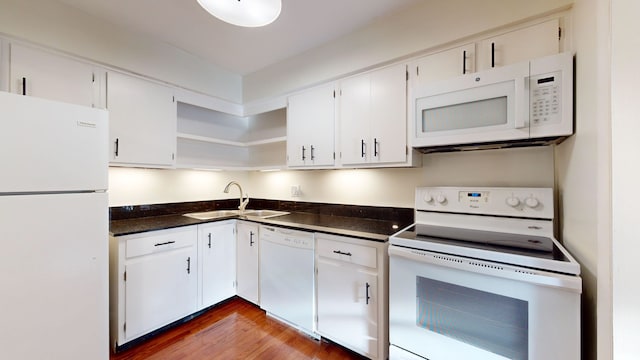 kitchen with dark hardwood / wood-style floors, sink, white cabinets, dark stone counters, and white appliances