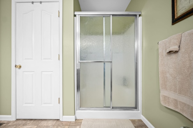 bathroom with an enclosed shower and tile patterned floors