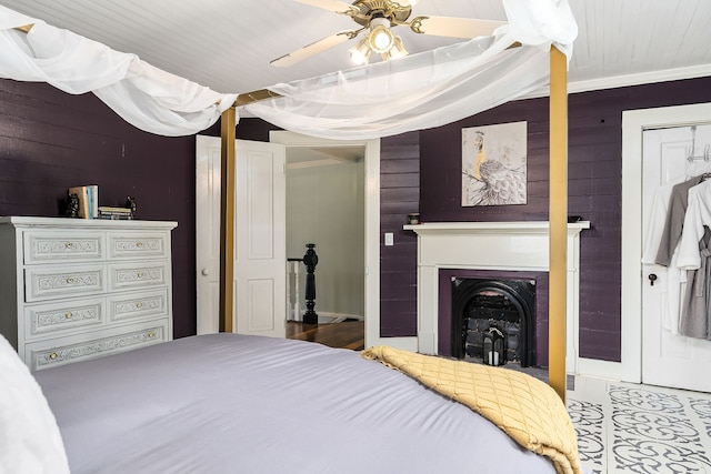 bedroom with ceiling fan, wood walls, and ornamental molding