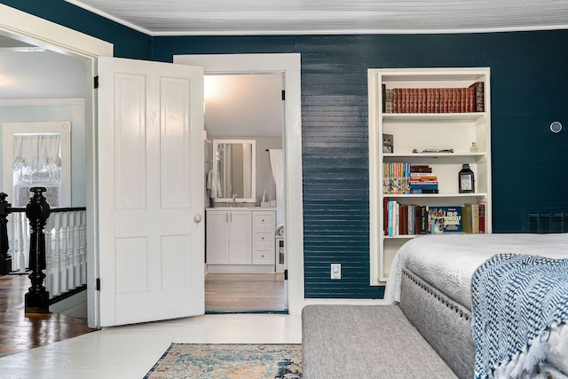 bedroom with hardwood / wood-style floors, crown molding, and sink