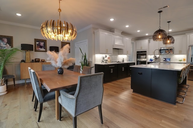 dining area with crown molding, an inviting chandelier, and light wood-type flooring