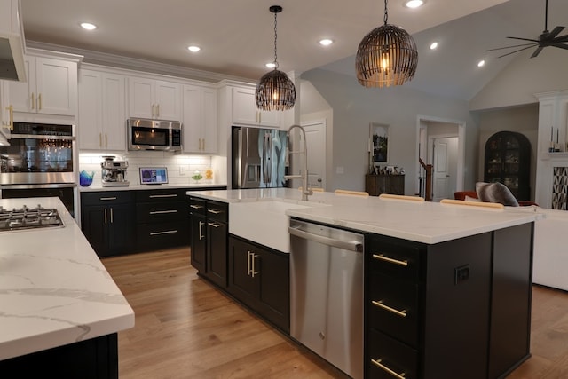 kitchen with appliances with stainless steel finishes, hanging light fixtures, and a center island with sink