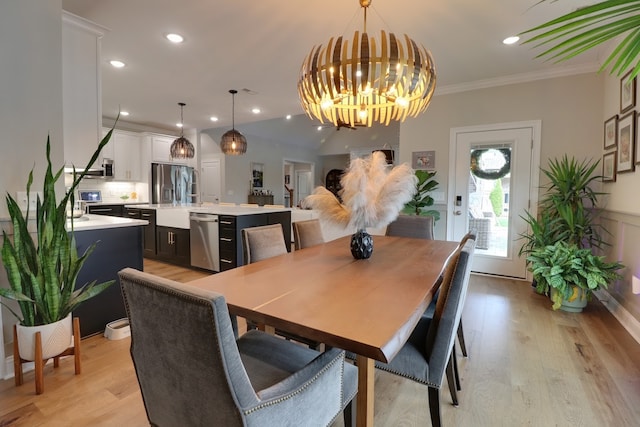 dining space with a notable chandelier, crown molding, and light hardwood / wood-style flooring