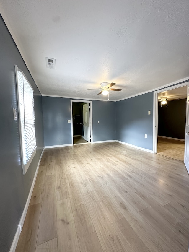 unfurnished room with ceiling fan, light wood-type flooring, a textured ceiling, and ornamental molding