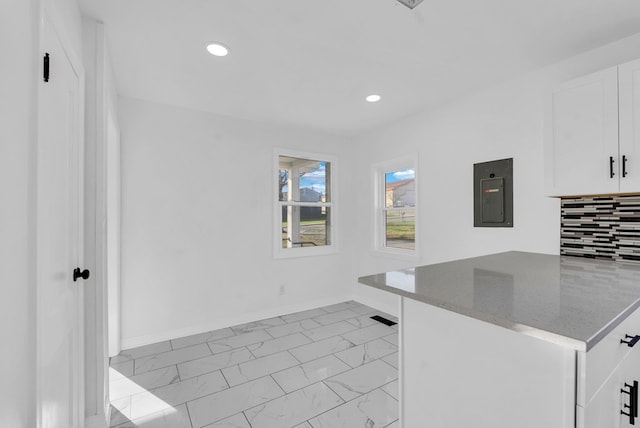 kitchen featuring backsplash, electric panel, white cabinetry, and stone countertops