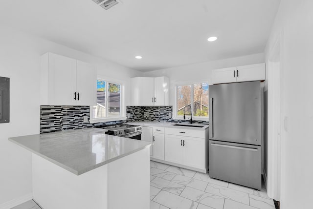 kitchen featuring white cabinets, kitchen peninsula, sink, and appliances with stainless steel finishes