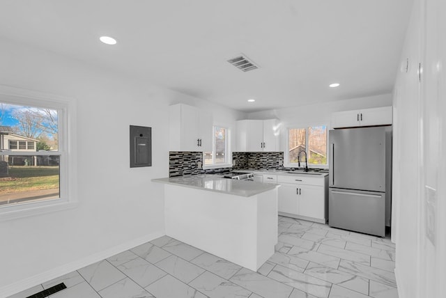 kitchen featuring kitchen peninsula, tasteful backsplash, stainless steel appliances, sink, and white cabinets