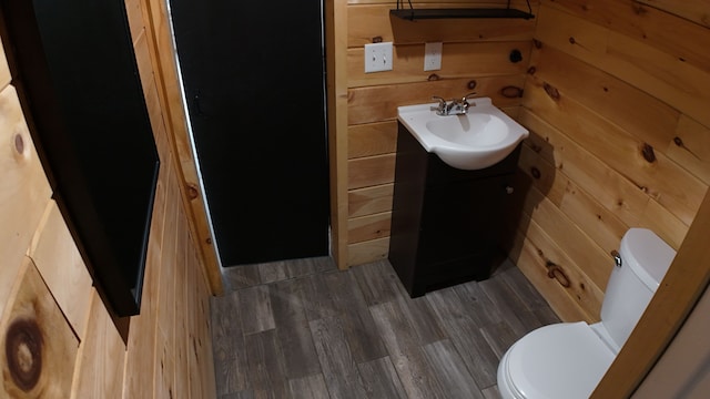 bathroom featuring vanity, wood walls, toilet, and wood-type flooring