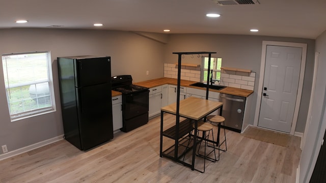 kitchen featuring white cabinetry, tasteful backsplash, light hardwood / wood-style floors, vaulted ceiling, and black appliances